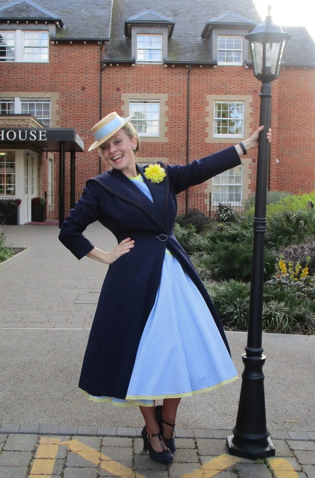Fiona Harrison in a navy and blue 1940s dress beside a lamppost